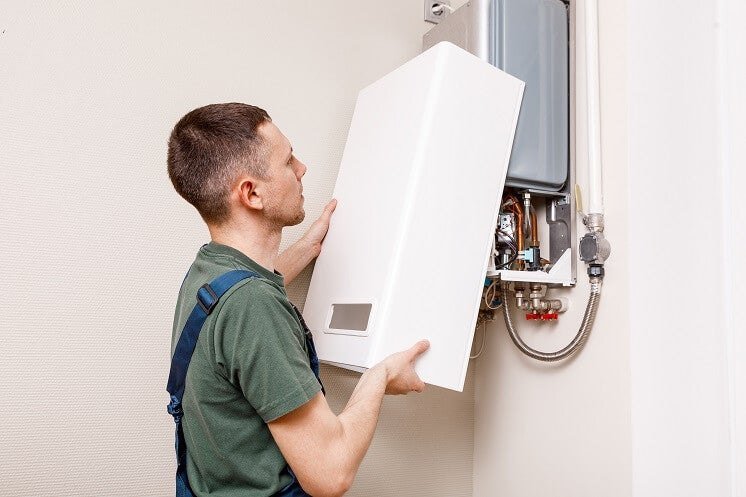 Gas engineer fitting a wall-mounted combi boiler